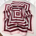 Detail of a square silk scarf featuring a geometric pattern in burgundy, black, and white - Dark Red