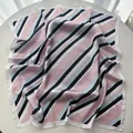 Pink and navy blue striped satin square scarf with white borders on a white table - Pink
