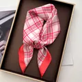 Elegant pink and red plaid silk scarf displayed on a luxury jewelry tray - Red