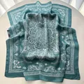 Teal square silk scarf with white mandala paisley print draped on a white table - Malachite green
