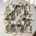 Detail of silk square scarf featuring olive green leaf patterns and elegant satin texture - Khaki