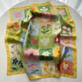 Detail of oil painting floral silk square scarf with vibrant yellow border on white table - Yellow