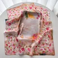 Pink silk-like square scarf with elegant floral and feather prints on a white table - Orange Red