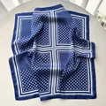Detail of blue and white polka dot silk scarf with smooth edges on a white table - Blue
