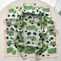 Detail of green leopard print silk scarf showing abstract patterns and silky fabric texture - Light Green