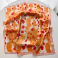 Detailed view of leopard print silk scarf with satin finish and orange artistic pattern - Orange