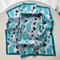 Detailed close-up of colorful leopard print silk scarf with fine stitched edges and glossy texture - Sky Blue