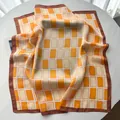 Detailansicht des Seidenschals mit orangefarbenem geometrischem Muster und braunem Rand - Sonnenblumengelb