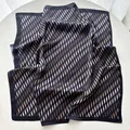 Detalle de elegante pañuelo de seda con estampado de ondas, costura fina y acabado satinado - Negro