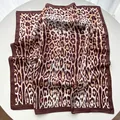 Detailed view of the smooth leopard print silk satin scarf with dark brown bordered edges - Coffee