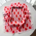 Nahaufnahme des geometrisch karierten Seidenschals in Rot und Rosa mit Satin-Glanz-Struktur - Rot