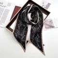 Close-up of floral print satin scarf with bow details and elegant beige piping trim - Black