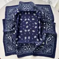 Macro detail of navy blue paisley silk scarf showing the elegant drape and smooth texture - Blue