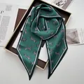 Detailed close-up of dark green zebra print satin scarf displayed on a stylish tray - Green