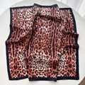 Macro detail of silk-satin leopard print scarf with bold orange and black border - Black