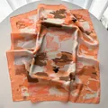 Detail of the abstract floral print and smooth texture on the large square silk scarf - Orange
