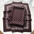 Detail view of smooth silk-like dark brown square scarf with white paisley patterns - Coffee