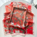 Detail of red silk scarf with white almond blossom print showing glossy satin texture - Pink