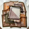 Detailansicht eines Seiden-Halstuchs mit Paisley-Muster in Erdtönen auf Tisch - Olivgrün