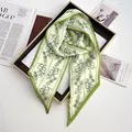 Detail of green floral skinny silk scarf with bow pattern on brown display tray - Light Green
