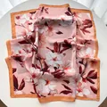 Detail of elegant pink silk square scarf with floral print and bronze border on table - Khaki