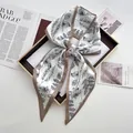 Elegante foulard in raso bianco con stampa floreale nera annodato a fiocco sul vassoio - Cachi