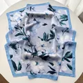 Detail of silk square scarf featuring light blue floral patterns on smooth fabric - Sky Blue
