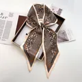 Detail of a chic houndstooth and paisley silk scarf tied in a bow inside a gift box - Turmeric