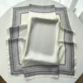 Eleganter cremefarbener Seidenschal mit schwarzem Paisleymuster und weichem Faltenwurf - Weiß