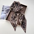 Detail view of leopard print silk scarf tied in a bow on a brown display tray - Classic Brown & Black Leopard Print Satin Style (Style 42)