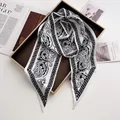 Detail of elegant black and white paisley silk scarf with satin texture on a tray - White