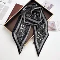 Close-up of paisley print silk scarf with chain patterns on a gold-edged tray - Black