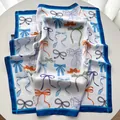 Detailed view of large square silk scarf with vibrant colorful bow print and blue border - Sky Blue