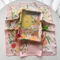 Détail d'un foulard carré en satin de soie avec imprimé floral et bordure rose - Rose