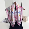 Detailed close-up of a silk square scarf featuring colorful bow prints and pink borders - Peach