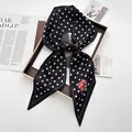 Close-up of geometric silk scarf with black white dots and pink floral pattern - Black