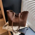 Minimalist large brown lychee leather tote bag for women shown on a beige trench coat - Coffee