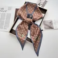 Close-up of caramel and blue polka dot silk scarf with floral print in a gift box - Khaki