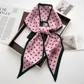 Detail of pink polka dot silk scarf tied in a bow on a stylish fashion magazine - Pink