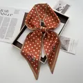 Terracotta polka dot silk scarf with lotus print tied in a bow on a dark tray - Chocolate