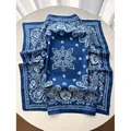Dark blue silk scarf with white paisley patterns displayed on a white round table - Blue
