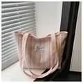 Dettaglio di una borsa tote in tela a righe rosa e gialle con etichetta logo di moda - Rosa