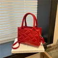 Rode gewatteerde leren handtas met gouden belettering op een wit decoratief boek - Rood