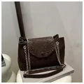 Detail view of dark brown snake pattern leather bag with golden chain and metal buckle - Brown