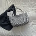 Borsa tote in tela a righe bianche e nere con tasca frontale in un elegante flat lay - Nero