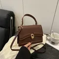 Dark brown leather crossbody bag featuring gold rings and adjustable shoulder strap - Brown