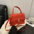Chic red leather handbag with golden ring lock and adjustable shoulder strap for women - Red