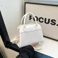 Detail der weißen Lederhandtasche mit gewebter Textur und goldenen Beschlägen - Weiß