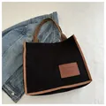 Minimalist black corduroy tote bag with brown woven handles and leather fashion patch - Black