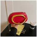 Detalle de mini bolso rojo con asa grande dorada en forma de C y cadena de serpiente fina - Rojo